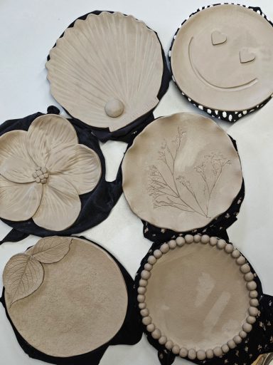 Diverse kleiobjecten in verschillende vormen en texturen, waaronder bloemen en gezichten.