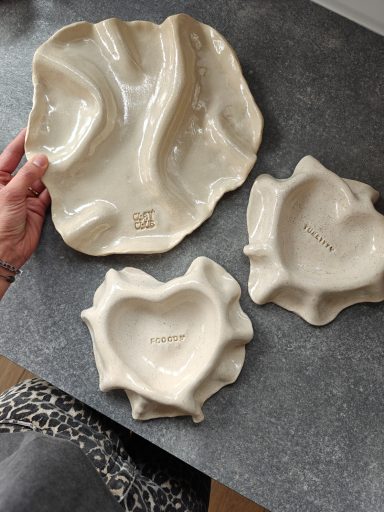 Drie keramische borden in organische vormen, een hartvormig en twee met golfachtige randen.