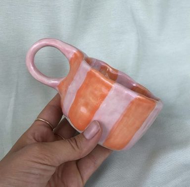 Handgemaakt kopje met roze en perzik gestreepte ontwerpen.
