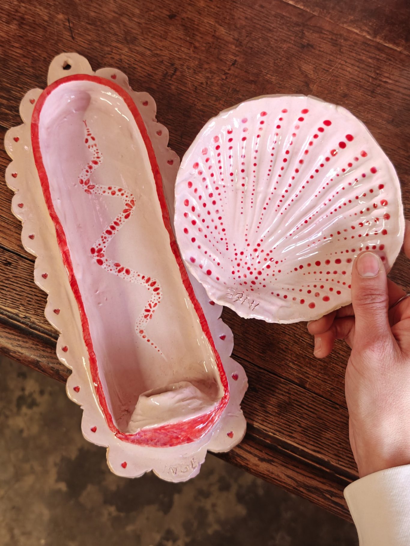 Handgemaakt, roze schelpvormig object met een open bovenkant en decoratieve rand.