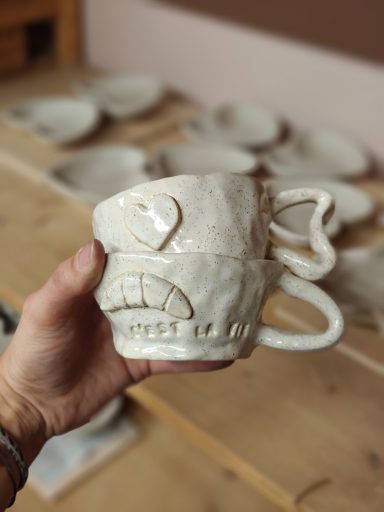 Unieke, handgemaakte witte mok met gezichtsontwerp en twee handvatten.