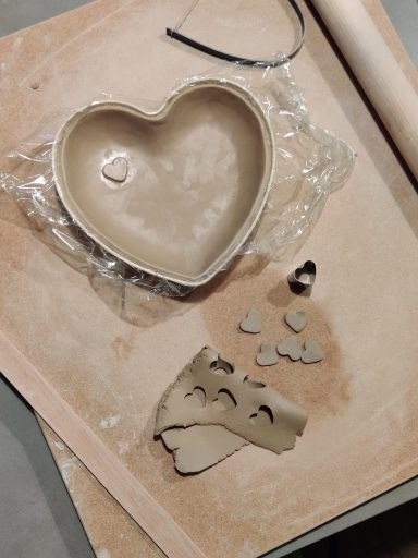 Een hartvormige kleischaal met restjes klei en gereedschap op een werkblad.