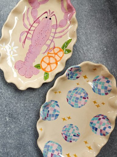 Twee schalen met kleurige, handgeschilderde kreeft en discoballen met glazuur beschilderd