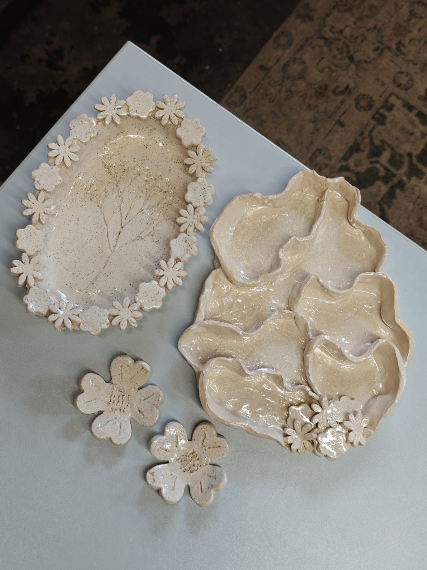 Decoratieve schalen en bloemenmotieven in lichte tinten op een tafel.